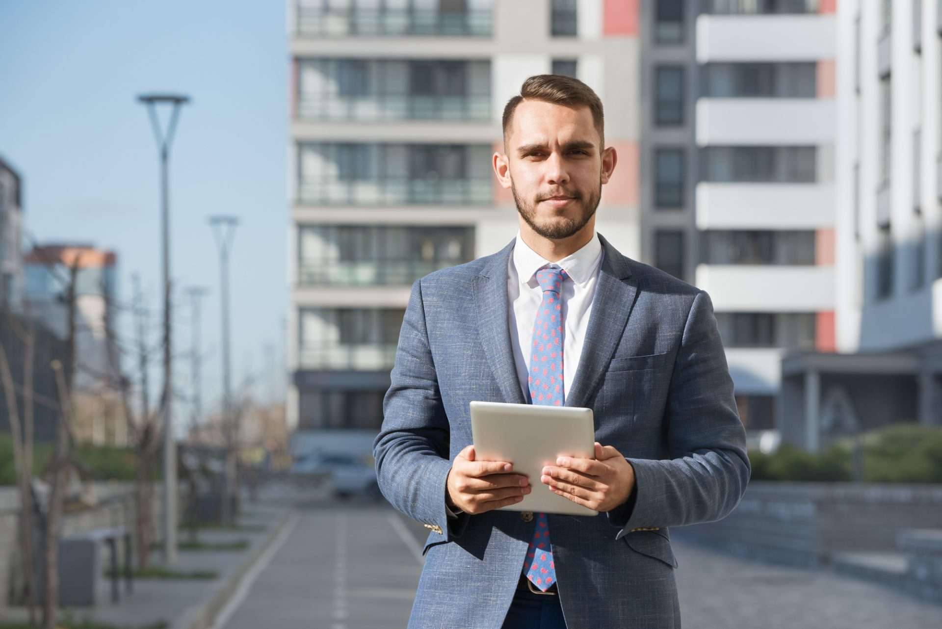 Businessman or real estate agent with tablet computer against new building